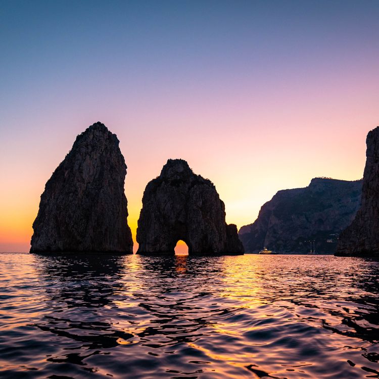 Capri Faraglioni Rocks at sunset — romantic couple boat ride.